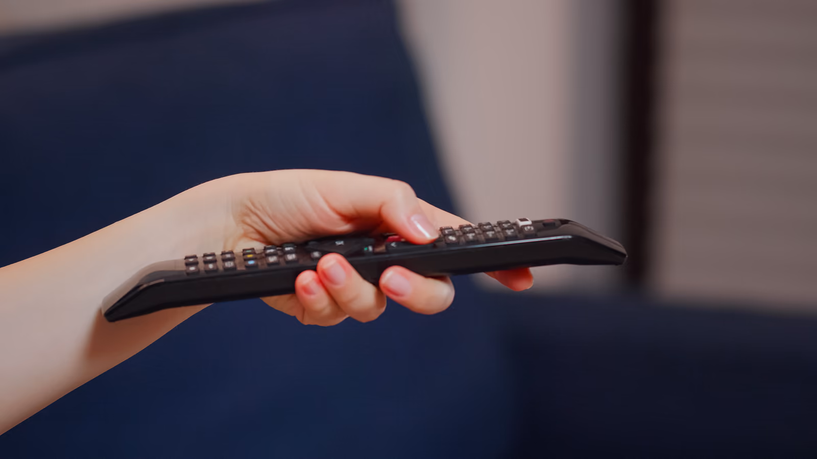 Persona usando el control remoto para automatizar los ajustes de un televisor inteligente