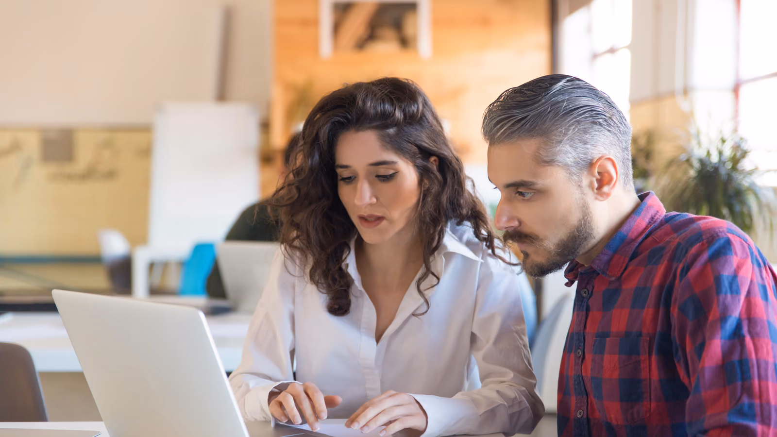 Dos personas revisando el proyecto de una web en un portátil, en una oficina Dos personas revisando el proyecto de una web en un portátil, en una oficina