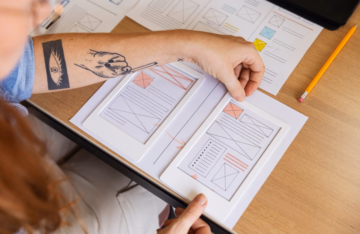 Persona dibujando bocetos de páginas web sobre papel